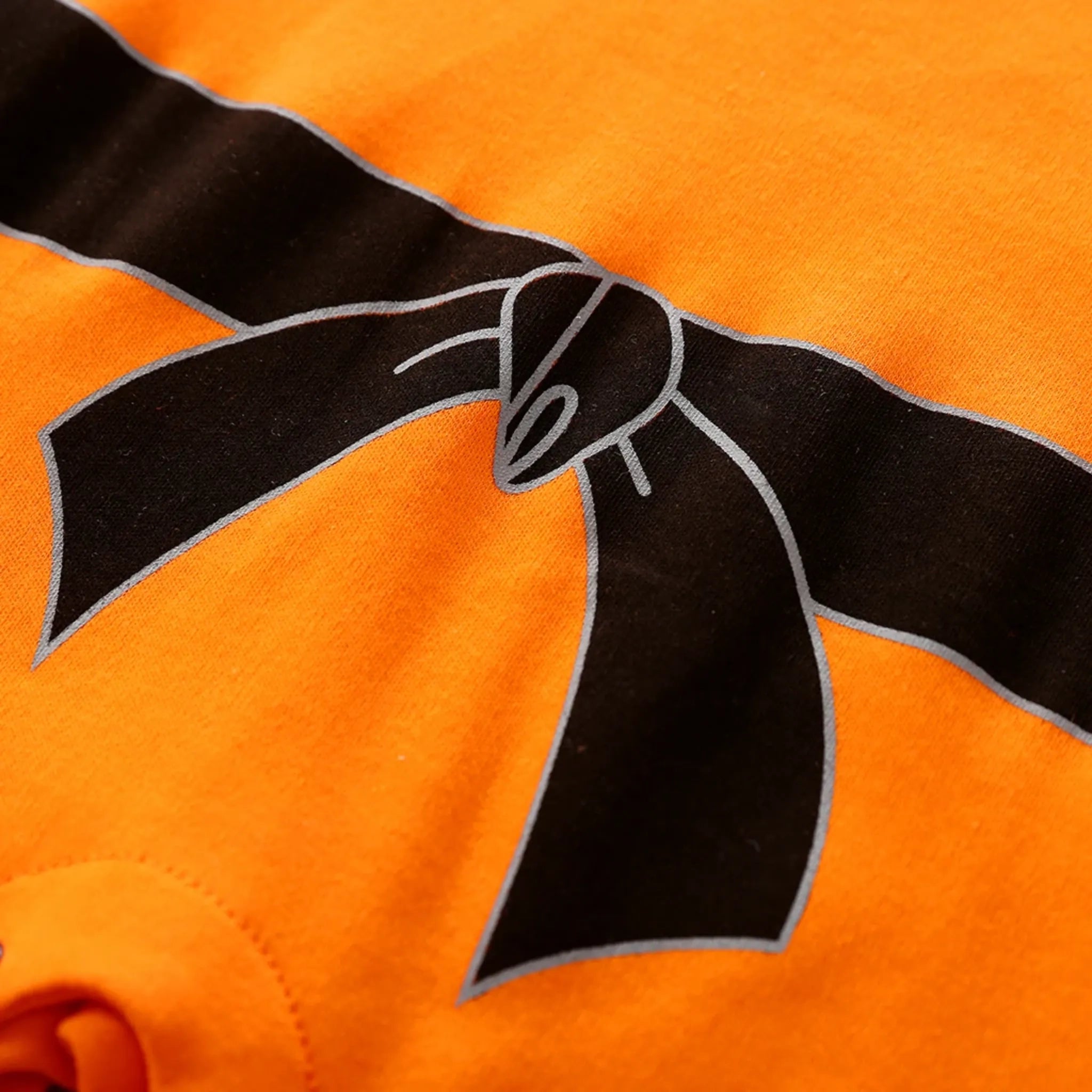 Zoom sur la ceinture noire imprimée du body Goku bébé – design fidèle à l’uniforme Dragon Ball